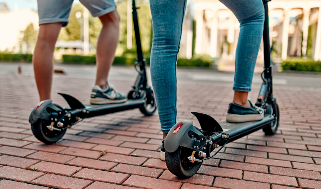 Two people riding scooters
